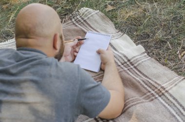 kel adam parkta bir çim üzerinde yalan