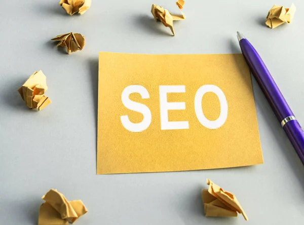 SEO- search engine optimization, words on yellow square paper, crumpled sheets and a pen are scattered nearby. Idea, vision, strategy, analysis, key words and concept of the content