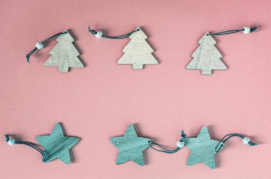 Tahta Noel oyuncakları, Noel ağaçları ve yıldızlar pembe arka planda iki sıra halinde dizilir. Basit biçimi temizle