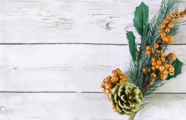 Noel süslemeleri turuncu böğürtlenli ladin dalları ve açık ahşap zemin üzerinde kahverengi çam kozalaklarıyla yapıldı. Metin için alan, üst görünüm, düz düzen. Dal sağ tarafta.