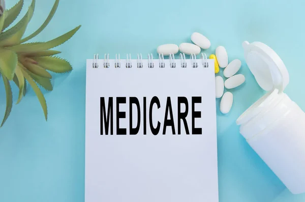 Medicare inskriptionen på anteckningsblocket bredvid tabletter och blomma, vy ovanifrån — Stockfoto