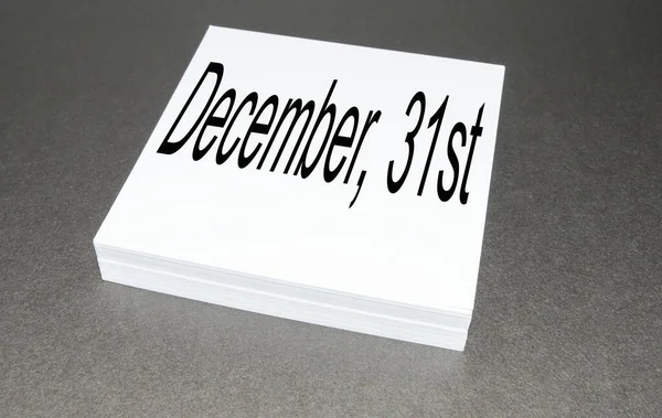 On a stack of square note paper is written December 31, the last day of the year, on a black background — Stock Photo, Image