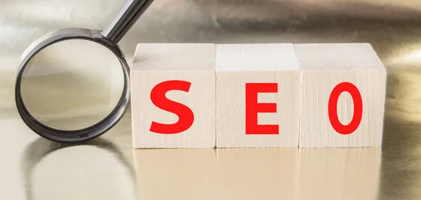 SEO search engine optimization text wooden cubes and magnifying glass on a Golden background. Idea, vision, strategy, analysis, Keyword and content concept