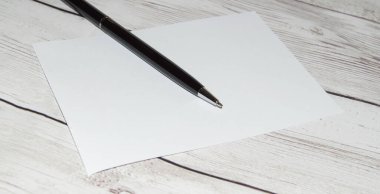 Boş bir defter ve açık tahta bir masa üzerinde siyah bir kalem, boşluğun bir kopyası, temiz bir sayfa açma kavramı.