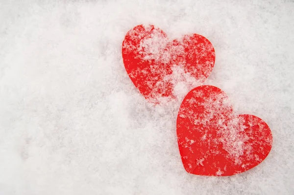 Karla kaplı iki güzel romantik kırmızı kalp, beyaz karlı bir arka planda. Aşk ve Sevgililer Günü kavramı
