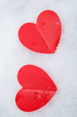 İki güzel romantik kırmızı kalp, dikey çerçeve, beyaz karlı arka planda birlikte. Aşk ve Sevgililer Günü kavramı