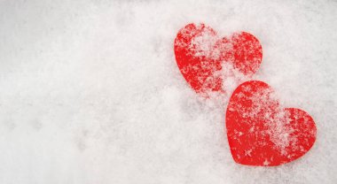 Karla kaplı iki güzel romantik kırmızı kalp, beyaz karlı bir arka planda. Aşk ve Sevgililer Günü kavramı