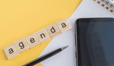 Masaüstündeki tahta küplere yazılmış plan. Kalem, telefon ve kağıt. Sarı arka plan, üst manzara, düz düzen.