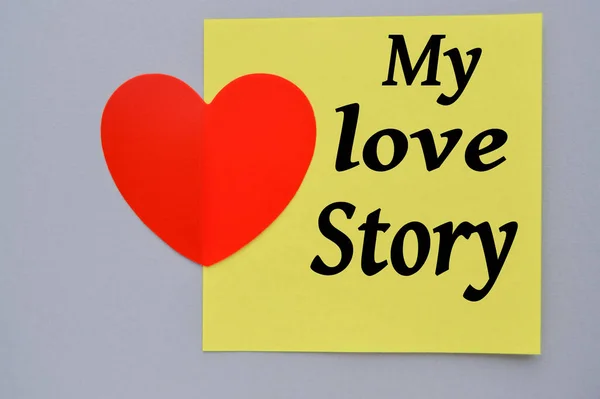 Benim hikayem, sarı kare bir kağıda yazılmış, dekoratif bir kalbi ve gri bir arka planı var. Sevgililer Günün kutlu olsun Şubat.