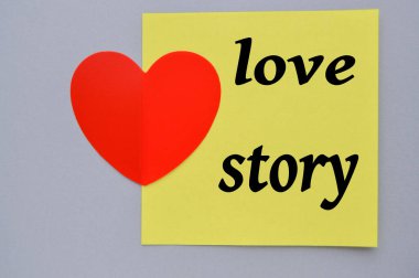 Sevgi Hikayesi, sarı kare kağıda yazılmış, dekoratif kalbi olan, gri arka planı olan. Sevgililer Günün kutlu olsun Şubat