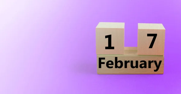 Calendario en forma de cubo de madera para el 17 de febrero sobre un fondo púrpura degradado con un espacio en blanco para el texto —  Fotos de Stock