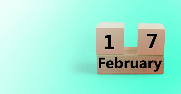 Träkub formad kalender för 17 februari på en lutning ljusblå bakgrund med ett tomt utrymme för text — Stockfoto