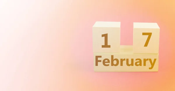 Calendario en forma de cubo de madera para el 17 de febrero sobre un fondo rosa amarillo degradado con un espacio en blanco para el texto —  Fotos de Stock