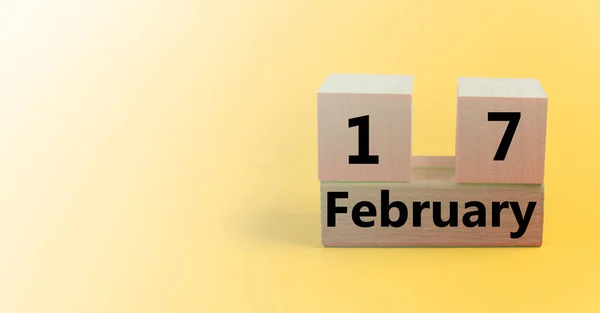 Calendario en forma de cubo de madera para el 17 de febrero sobre un fondo amarillo degradado con un espacio en blanco para el texto —  Fotos de Stock