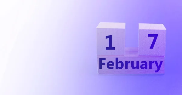 Calendario en forma de cubo de madera para el 17 de febrero sobre un fondo púrpura degradado con un espacio en blanco para el texto —  Fotos de Stock