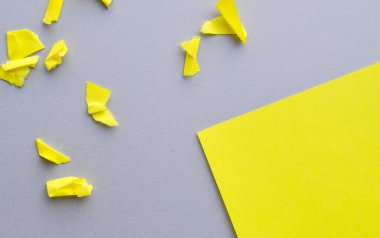 Gri arkaplandaki boşluğun bir kopyasının olduğu köşe YELLOW kağıdı ve küçük yırtık ve buruşuk kağıt parçaları, tasarımınız için bir şablon