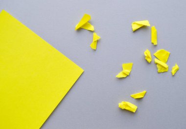 Gri arkaplandaki boşluğun bir kopyasının olduğu köşe YELLOW kağıdı ve küçük yırtık ve buruşuk kağıt parçaları, tasarımınız için bir şablon