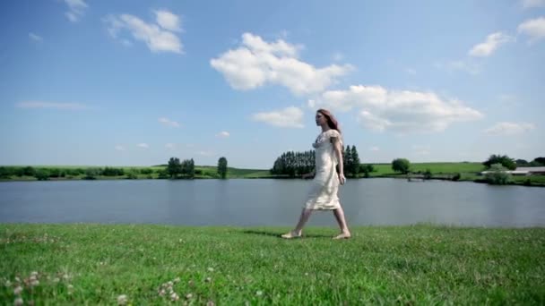 Jonge vrouw lopen in de buurt van lake — Stockvideo