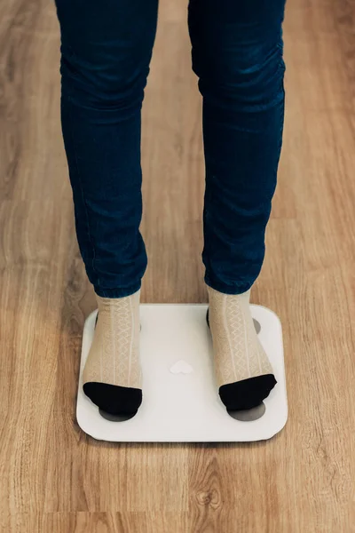 Chica mide peso en básculas inteligentes. Dispositivo electrónico moderno. — Foto de Stock