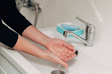 Kız enfeksiyonu önlemek için ellerini yıkar. Virüs COVID-19.