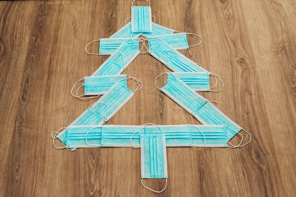 Árbol de Navidad hecho de máscaras médicas azules sobre un fondo marrón —  Fotos de Stock