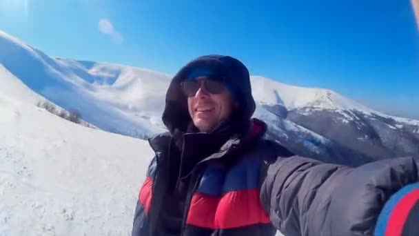 A fiatal, elégedett boldog fickó szelfit készít egy lenyűgöző téli táj hátterében. Kárpátok. — Stock videók