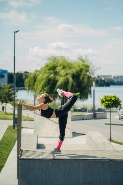 Göl kenarındaki spor sahasında egzersiz yapan bir kız. Sağlıklı yaşam tarzı kavramı.