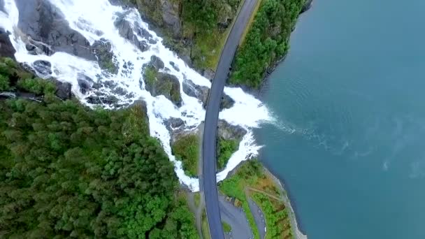 一座美丽的瀑布从陡峭的山中流进一条大河。空中风景。挪威. — 图库视频影像