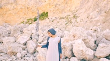 Güzel bir kadın elinde sihirli bir çim tutuyor taşların arka planında ve vadide. Sürrealizm.