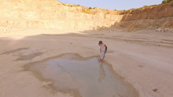 Aerial view. A beautiful girl in strange clothes near a large rain puddle on the background of a piano. Surrealism. — Stock Video