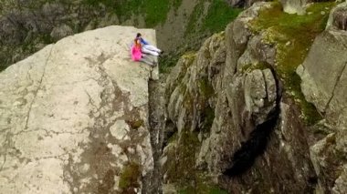 Adam ve bir kız yüksek bir uçurumun kenarında oturuyorlar. Ekstrem turizm. Norveç