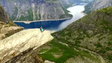 Hava görüntüsü. Kız yüksek bir uçurumun kenarında oturuyor. Ekstrem turizm. Norveç