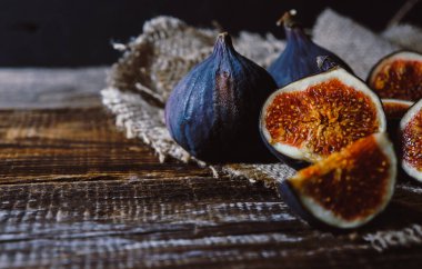 Birkaç incir bütün ve eski bir ahşap masa üzerinde doğranmış, kopyalama alanı