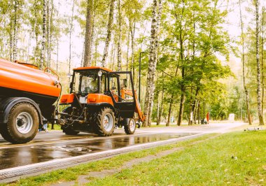 Parkın temizlenmesi, kaldırımı sulayan küçük bir traktör.