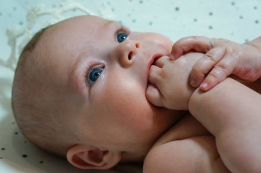 cute four month old baby sucking his fingers close up