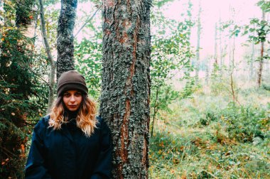 Çam ormanlarında poz veren, bahar ve sonbaharda sıcacık giysiler giyen güzel genç bir kız.