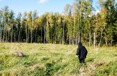 Sıcak giysiler içinde ormanda yürüyen bir kızın arka görüntüsü.