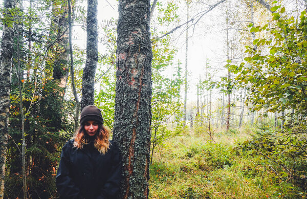 beautiful young girl posing in a pine forest, dressed in warm outerwear in spring and autumn