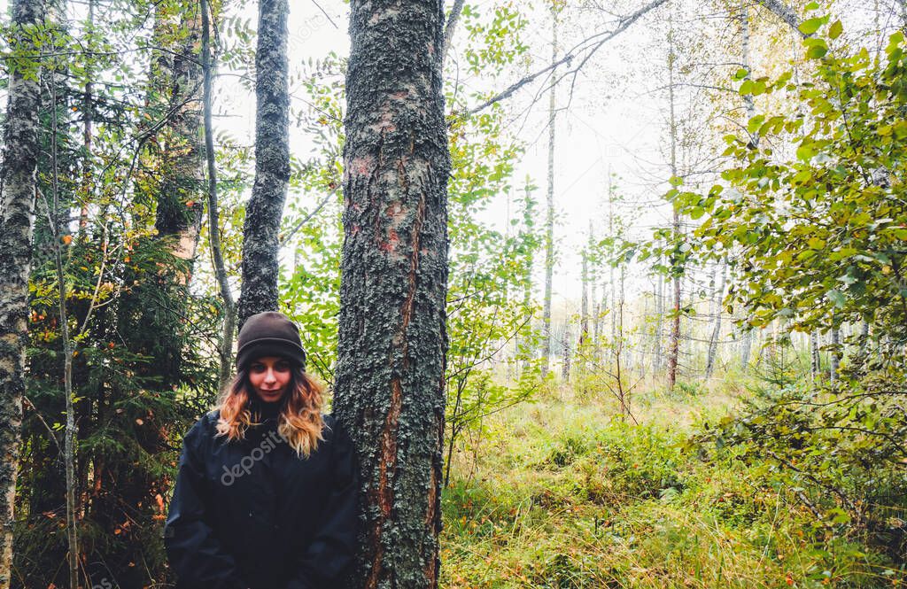 beautiful young girl posing in a pine forest, dressed in warm outerwear in spring and autumn