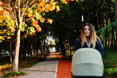 Sonbahar parkında bir çocukla yürüyen bir kızın portresi.