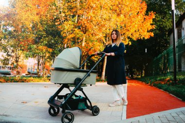 Sonbahar parkında bir çocukla yürüyen bir kızın portresi.