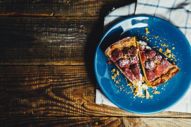 Ahududu ve çikolatalı cheesecake, ahşap bir masada beyaz bir tabakta.
