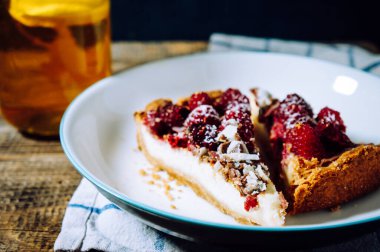 Ahududu ve çikolatalı cheesecake, ahşap bir masada beyaz bir tabakta.