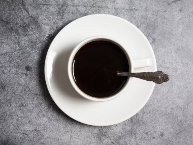 Beton arka planda beyaz bir fincanda sade kahve, boşluğu kopyalıyor.