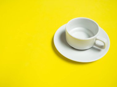 Sarı bir zemin üzerinde boş bir beyaz fincan ve bir fincan, boşluğun bir kopyası.