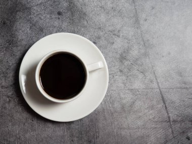 Beton arka planda beyaz bir fincanda sade kahve, boşluğu kopyalıyor.