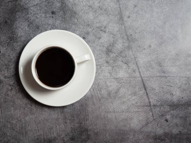 Beton arka planda beyaz bir fincanda sade kahve, boşluğu kopyalıyor.