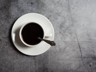 Beton arka planda beyaz bir fincanda sade kahve, boşluğu kopyalıyor.