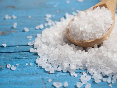 Deniz tuzu, ahşap bir kaşıkta eski ahşap bir arka planda deniz tuzu yığını.