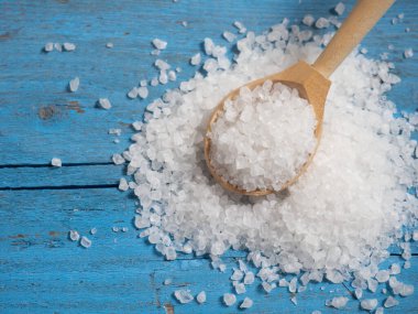 Deniz tuzu, ahşap bir kaşıkta eski ahşap bir arka planda deniz tuzu yığını.